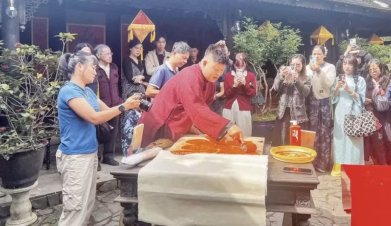응우옌 꽁 닷 장인이 후에의 응우 하 비엔 공간에서 쭈언 마을의 대련(대구)을 인쇄하고 있다. (사진: 만 하오)