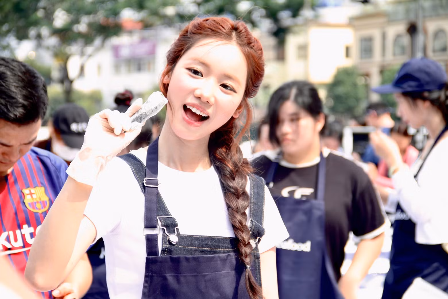 축제에서 한식 요리 체험에 밝은 표정으로 참여하는 젊은이들.