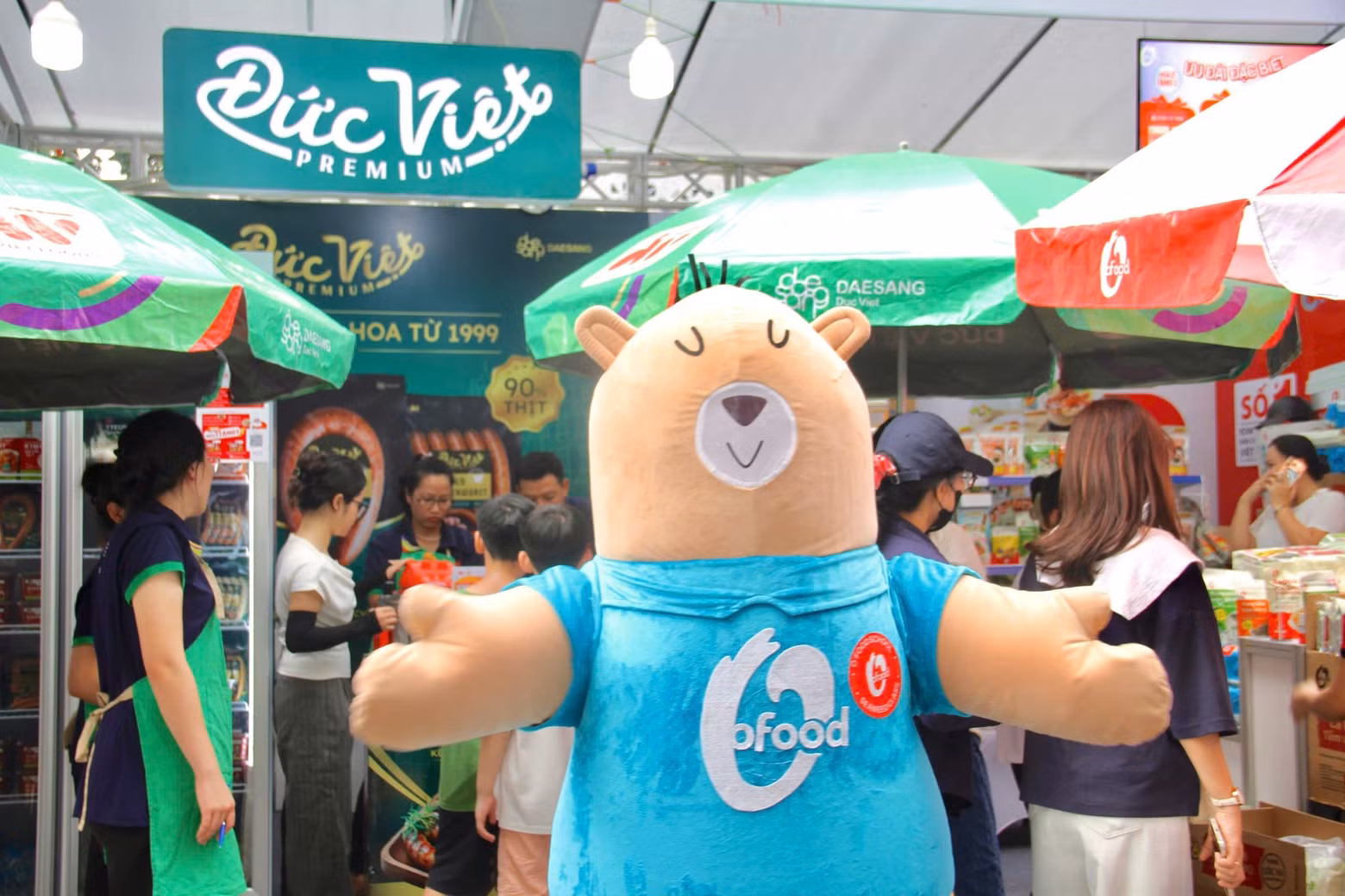 귀여운 마스코트 O'Food가 방문객들과 교류하며 Đức Việt-대상 식품 부스에 활기를 더하고 있다.