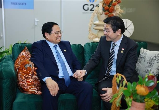 베트남 팜 민 찐 총리(왼쪽)와 싱가포르 로렌스 웡 총리가 23일 요하네스버그에서 만나 환담하고 있다. (사진: VNA)