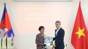 응우옌 민 부 캄보디아 주재 베트남 대사(오른쪽)가 2009년 베트남 총리로부터 공로 표창을 받은 대미 항전 유공자 하 티 에에게 설 선물을 전달하고 있다. (사진: VNA)